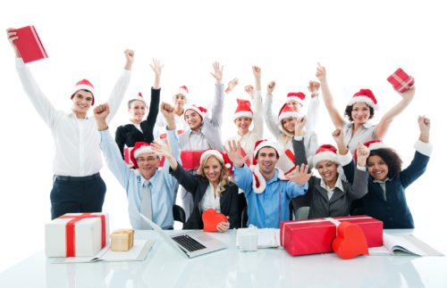 Large group of happy businesspeople with raised arms wearing Santa's hat and looking at camera. Isolated on white.